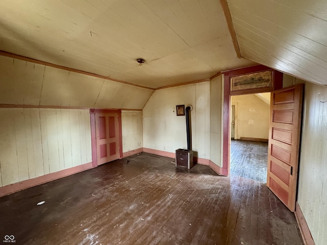 additional living space with lofted ceiling, dark wood-type flooring, and wood walls