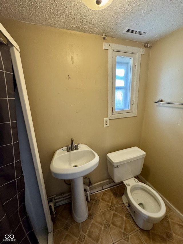 bathroom featuring tile patterned flooring, a textured ceiling, and toilet