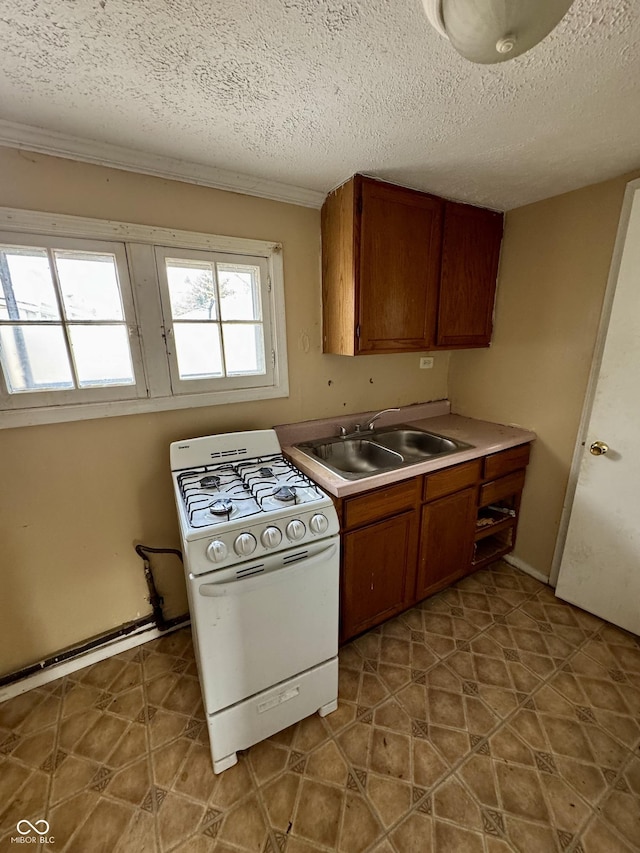 kitchen with sink, white gas stove, and a textured ceiling