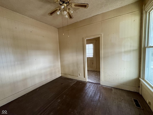 unfurnished room with dark wood-type flooring, a textured ceiling, and ceiling fan