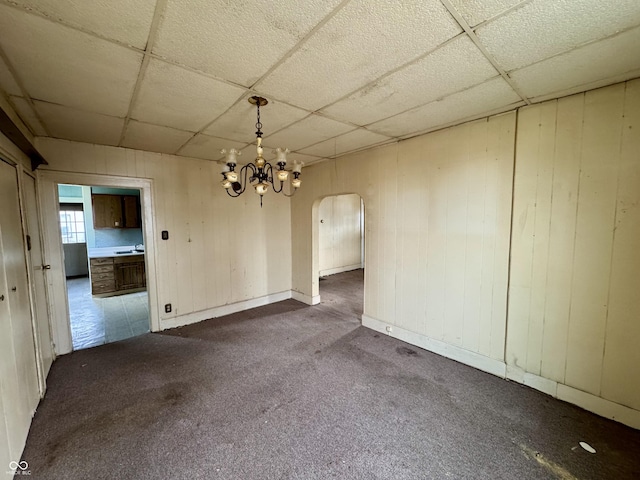 unfurnished room featuring carpet floors, a drop ceiling, and a chandelier