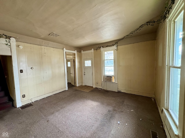 unfurnished room with cooling unit and wood walls