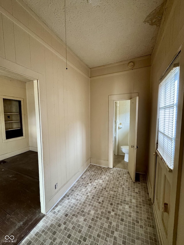 spare room with wooden walls and a textured ceiling