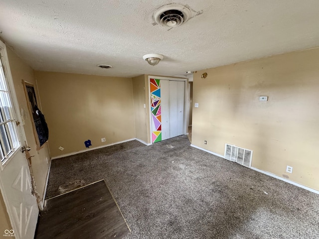 unfurnished room with dark carpet and a textured ceiling