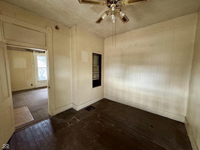 spare room with dark hardwood / wood-style floors, a textured ceiling, ceiling fan, and built in shelves