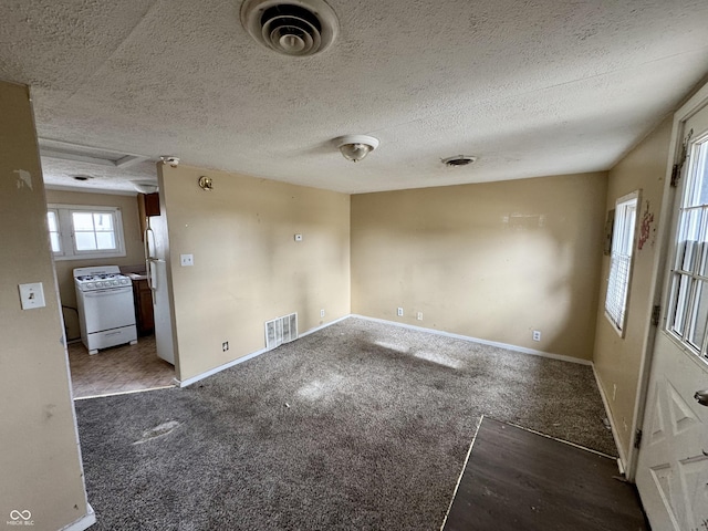 spare room with dark colored carpet and a textured ceiling