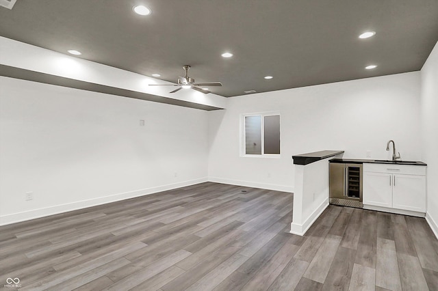 bar with sink, ceiling fan, white cabinetry, wine cooler, and light wood-type flooring