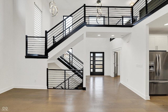 foyer featuring french doors, a towering ceiling, and wood-type flooring