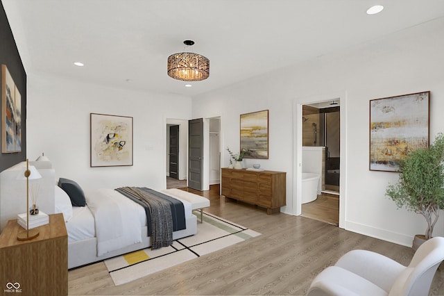 bedroom featuring connected bathroom and light hardwood / wood-style floors