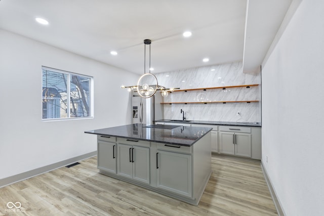 kitchen with pendant lighting, sink, gray cabinets, and a kitchen island