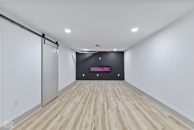 basement featuring a barn door and light hardwood / wood-style floors