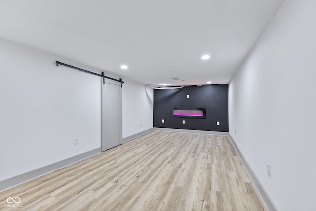 basement with a barn door and light hardwood / wood-style floors