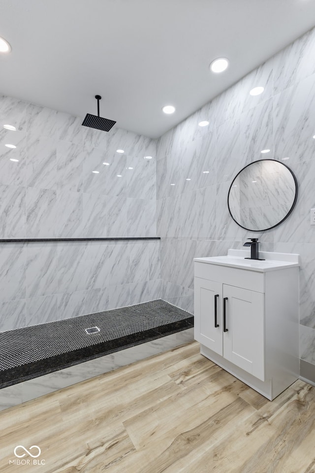 bathroom with vanity, wood-type flooring, tile walls, and walk in shower