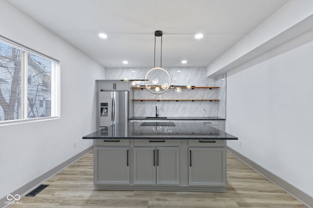 bar featuring hanging light fixtures, light hardwood / wood-style flooring, stainless steel fridge, gray cabinets, and dark stone counters