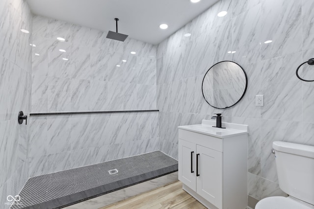 bathroom featuring toilet, tile walls, a tile shower, vanity, and hardwood / wood-style flooring