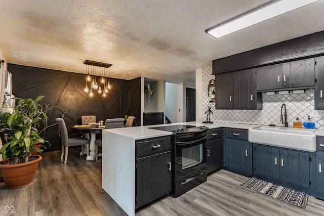 kitchen featuring black electric range, a peninsula, light countertops, and decorative light fixtures