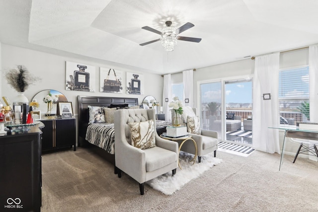 carpeted bedroom featuring ceiling fan, a tray ceiling, and access to outside