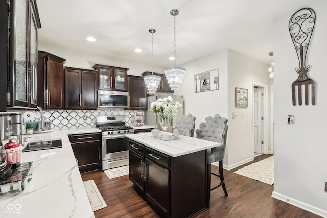 kitchen with stainless steel appliances, a kitchen island, a breakfast bar area, and hanging light fixtures