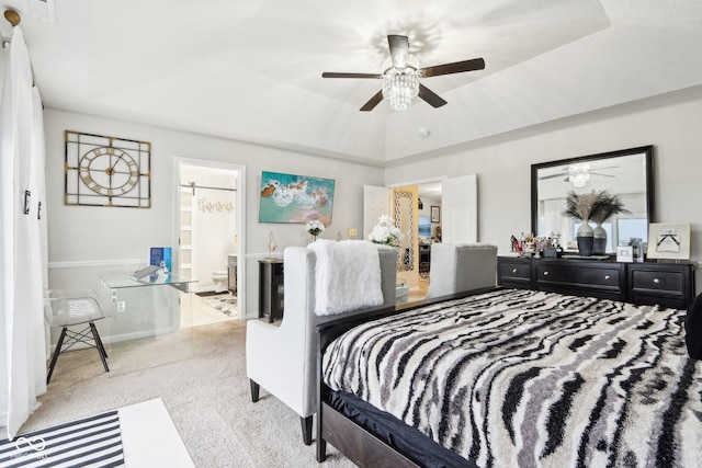 carpeted bedroom featuring ceiling fan, connected bathroom, and a tray ceiling