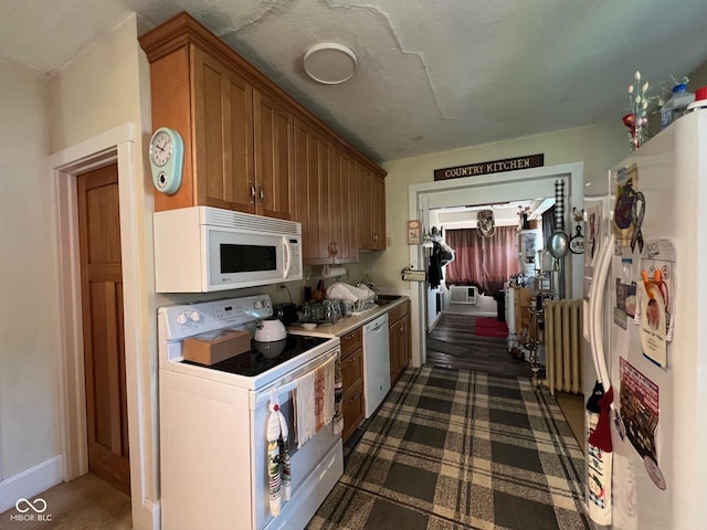 kitchen featuring radiator heating unit, a textured ceiling, and white appliances