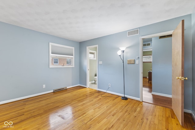 unfurnished bedroom with ensuite bath and light wood-type flooring