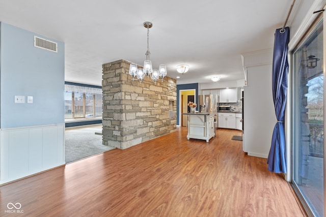 unfurnished dining area featuring an inviting chandelier and light hardwood / wood-style floors