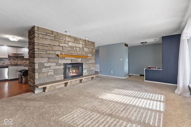 unfurnished living room featuring carpet flooring and a stone fireplace