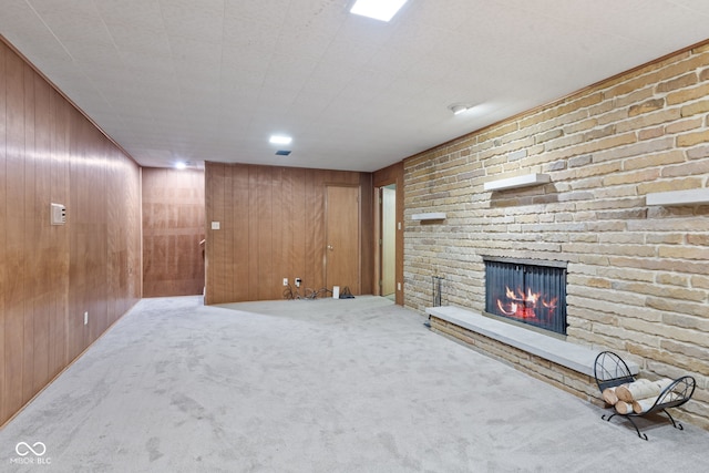 basement featuring a brick fireplace, carpet floors, and wood walls