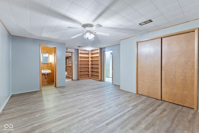 unfurnished bedroom with ensuite bathroom, sink, light hardwood / wood-style flooring, ceiling fan, and a closet