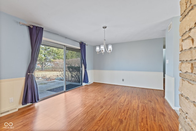 empty room featuring a chandelier and hardwood / wood-style floors