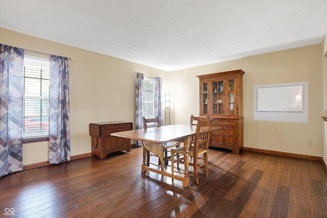 dining space featuring dark hardwood / wood-style flooring and a textured ceiling