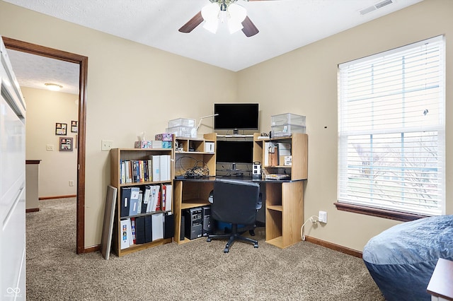 carpeted home office with ceiling fan and a textured ceiling