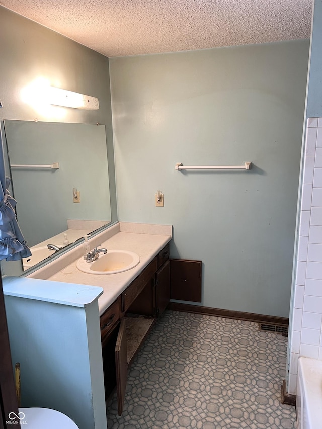 full bath featuring baseboards, toilet, a bathtub, a textured ceiling, and vanity