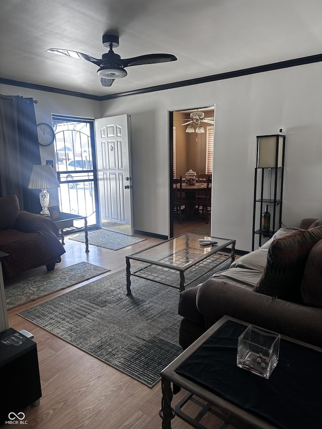 living room with ceiling fan, ornamental molding, and wood finished floors