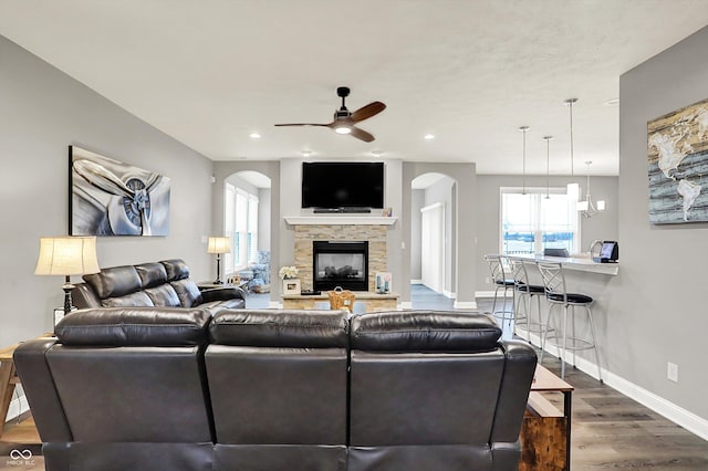 living room featuring wood-type flooring, ceiling fan, and a fireplace