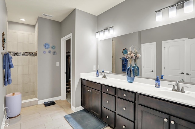 bathroom featuring vanity, tile patterned flooring, and a tile shower