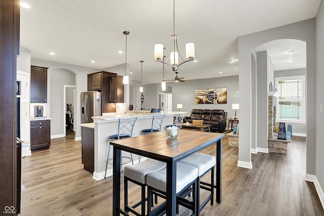 kitchen with hanging light fixtures, a breakfast bar, light hardwood / wood-style floors, and stainless steel fridge with ice dispenser