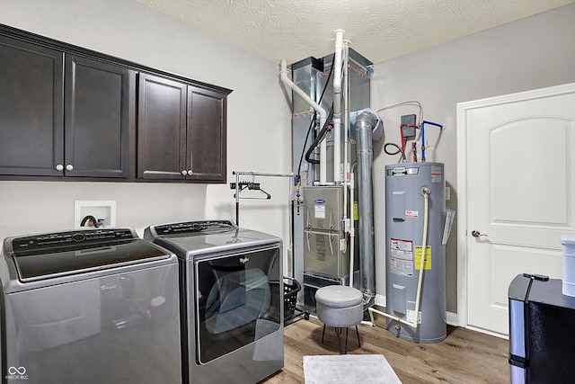 laundry area featuring separate washer and dryer, light hardwood / wood-style floors, water heater, and a textured ceiling