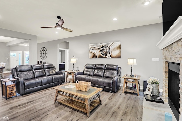 living room with a fireplace, light hardwood / wood-style floors, and ceiling fan