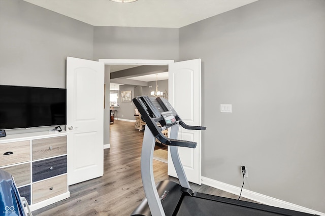 exercise area with hardwood / wood-style floors and a notable chandelier