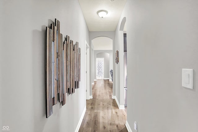 corridor featuring light hardwood / wood-style floors and a textured ceiling