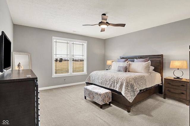 bedroom featuring ceiling fan, light carpet, and a textured ceiling