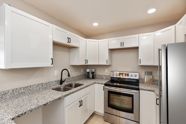 kitchen featuring white cabinetry, appliances with stainless steel finishes, sink, and light stone counters