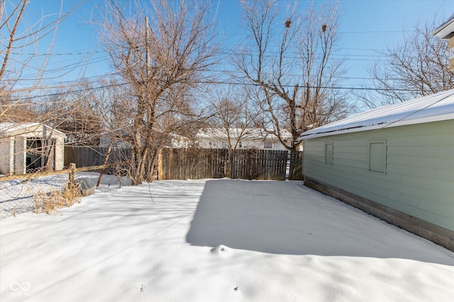 snowy yard featuring a storage shed