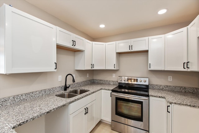 kitchen featuring light stone counters, sink, white cabinets, and stainless steel electric range oven