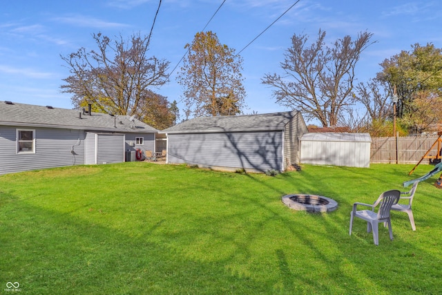 view of yard with a playground, a storage unit, and a fire pit