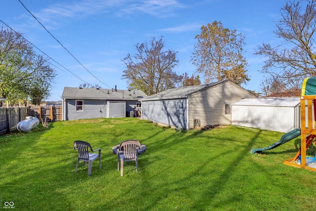 view of yard featuring a playground, an outbuilding, and a fire pit