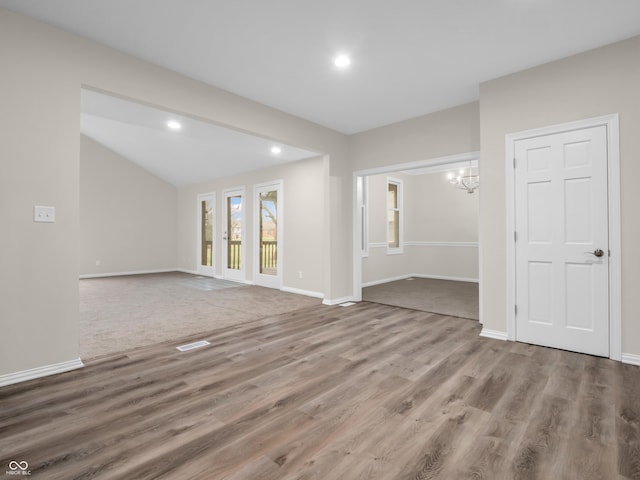 empty room featuring lofted ceiling, wood-type flooring, and a chandelier