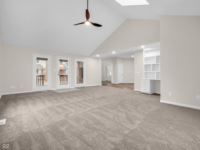 unfurnished living room featuring ceiling fan, carpet, high vaulted ceiling, and a skylight