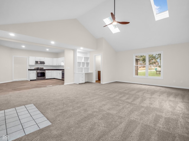 unfurnished living room with light carpet, a skylight, high vaulted ceiling, and ceiling fan